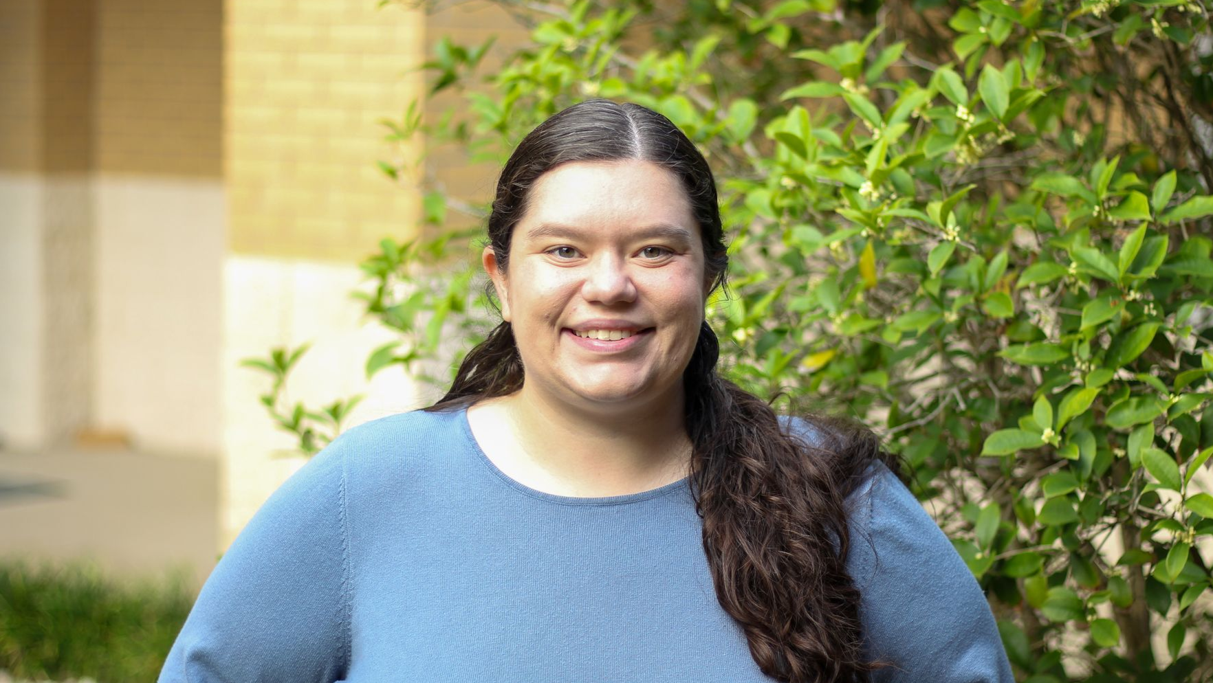 A young woman is smiling in front of a church.