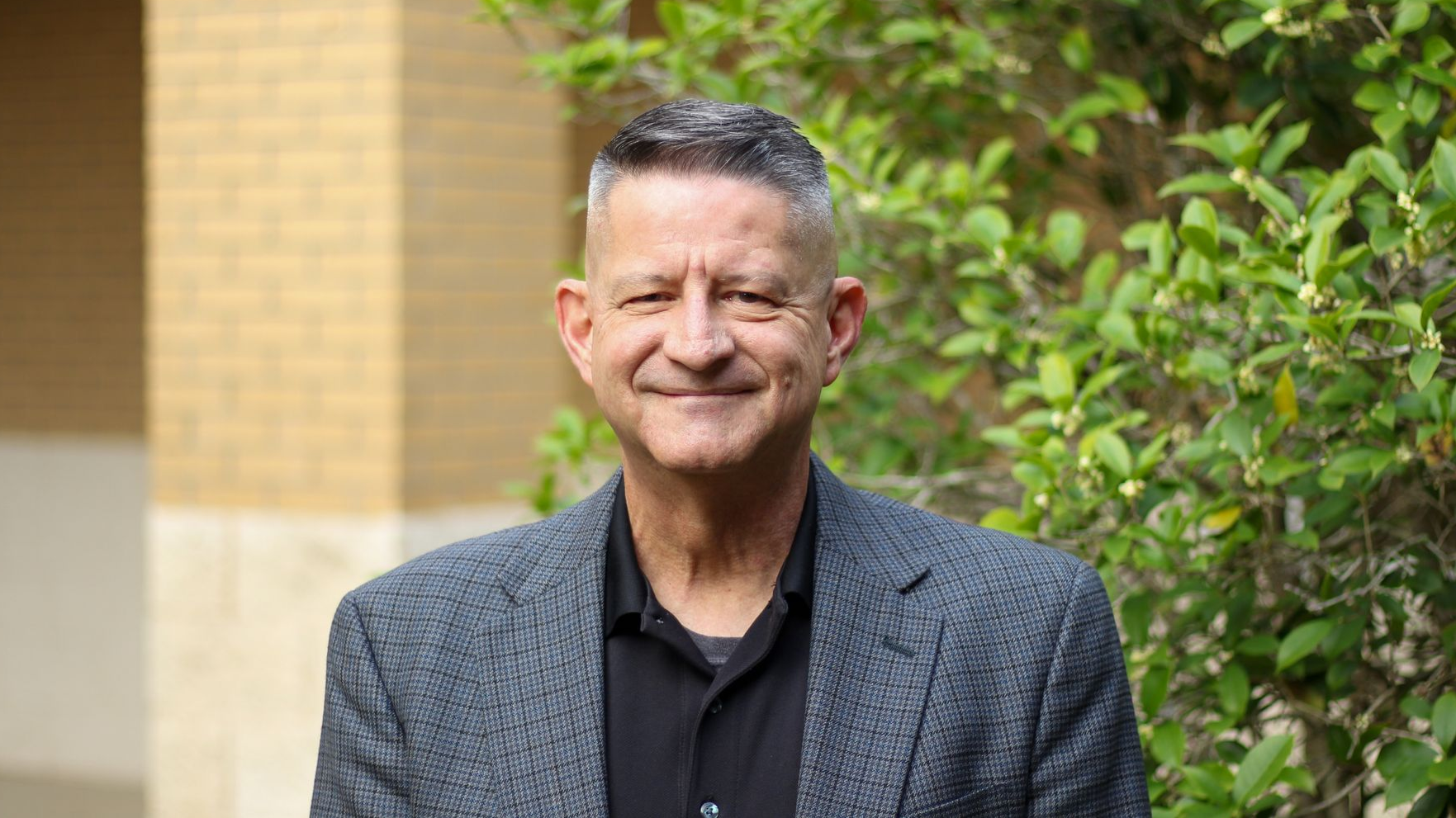 A man in a black shirt is smiling for the camera.