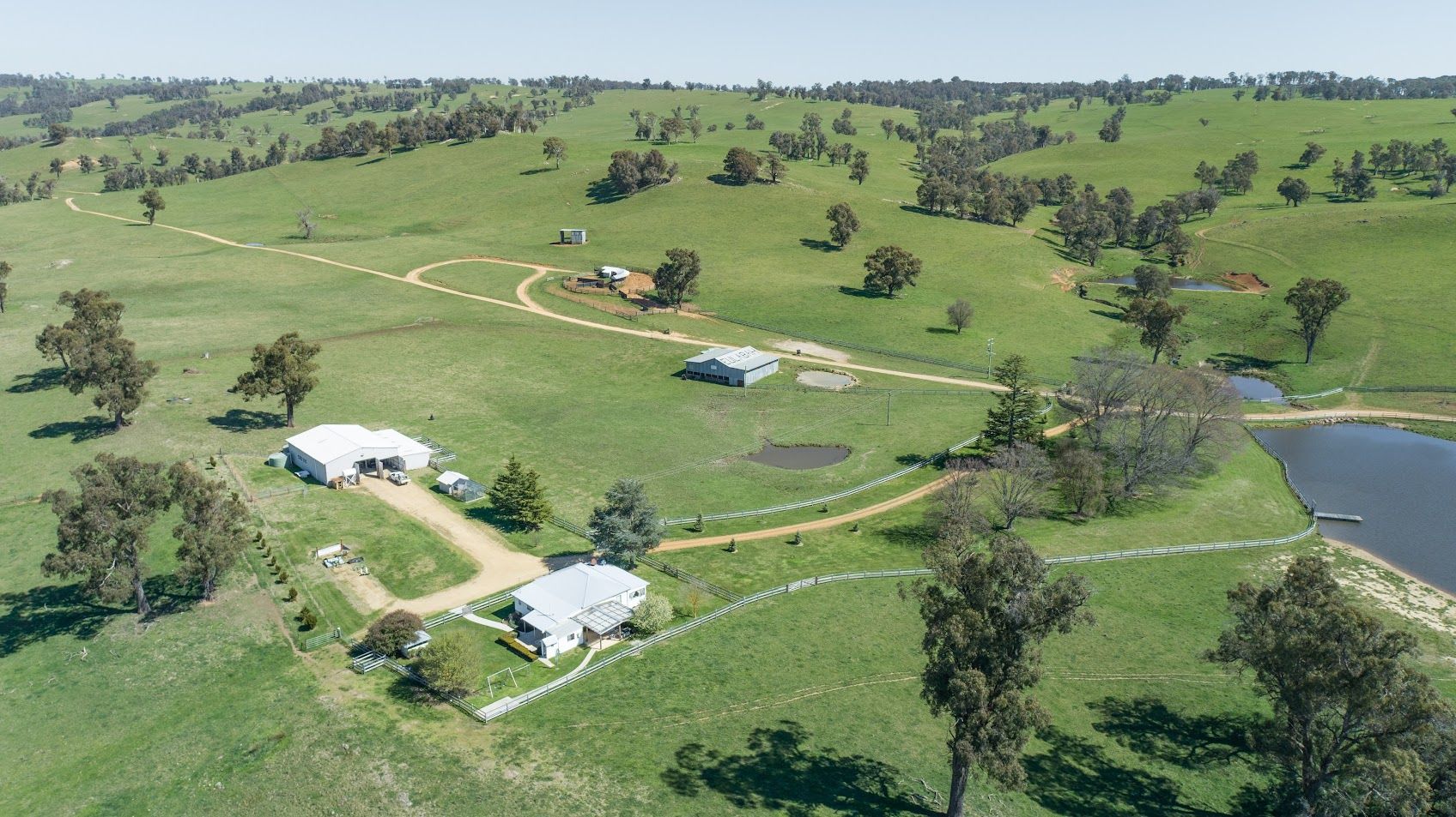 A white house is sitting in the middle of a lush green field.