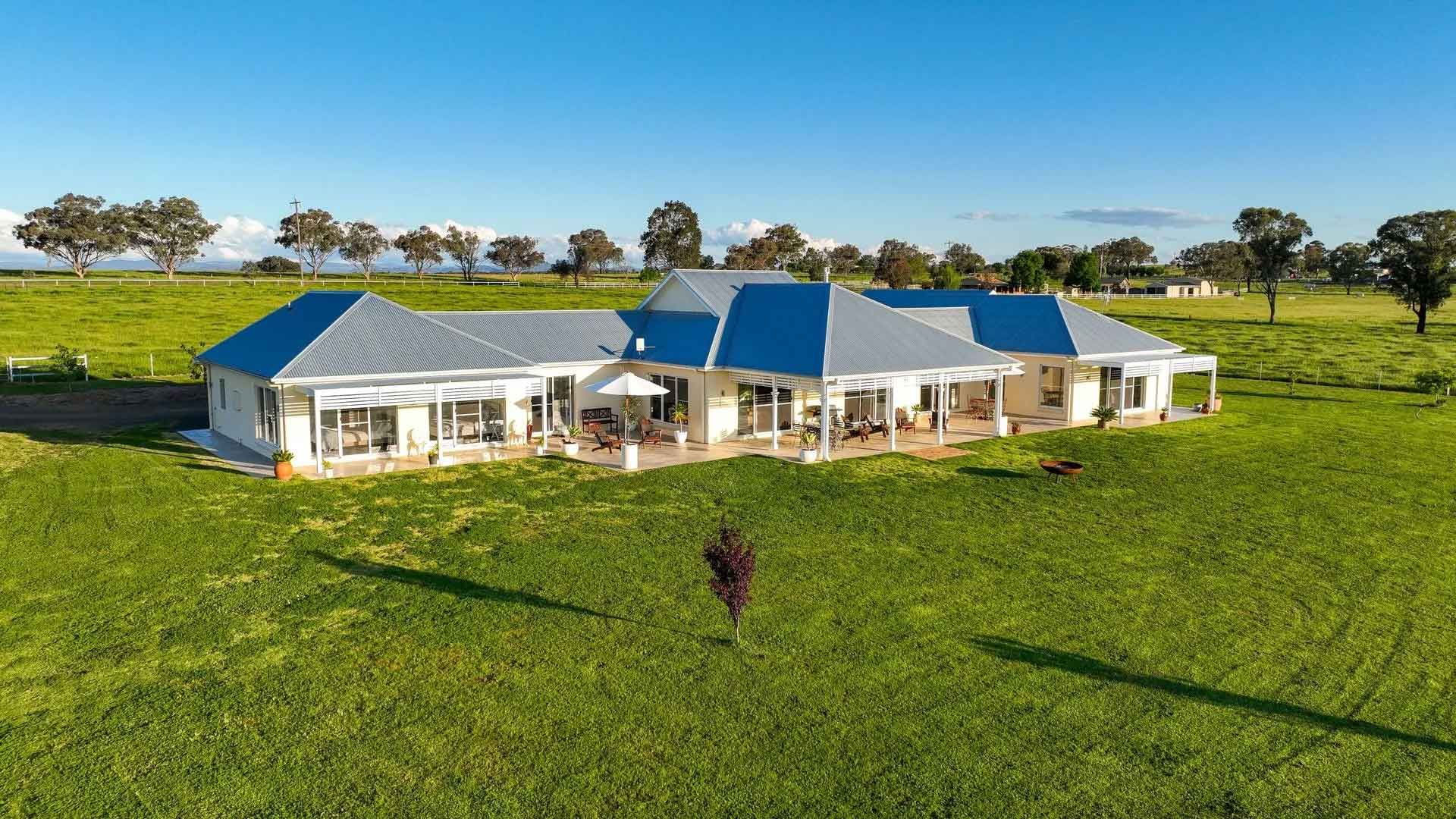 An aerial view of a large house in the middle of a grassy field.