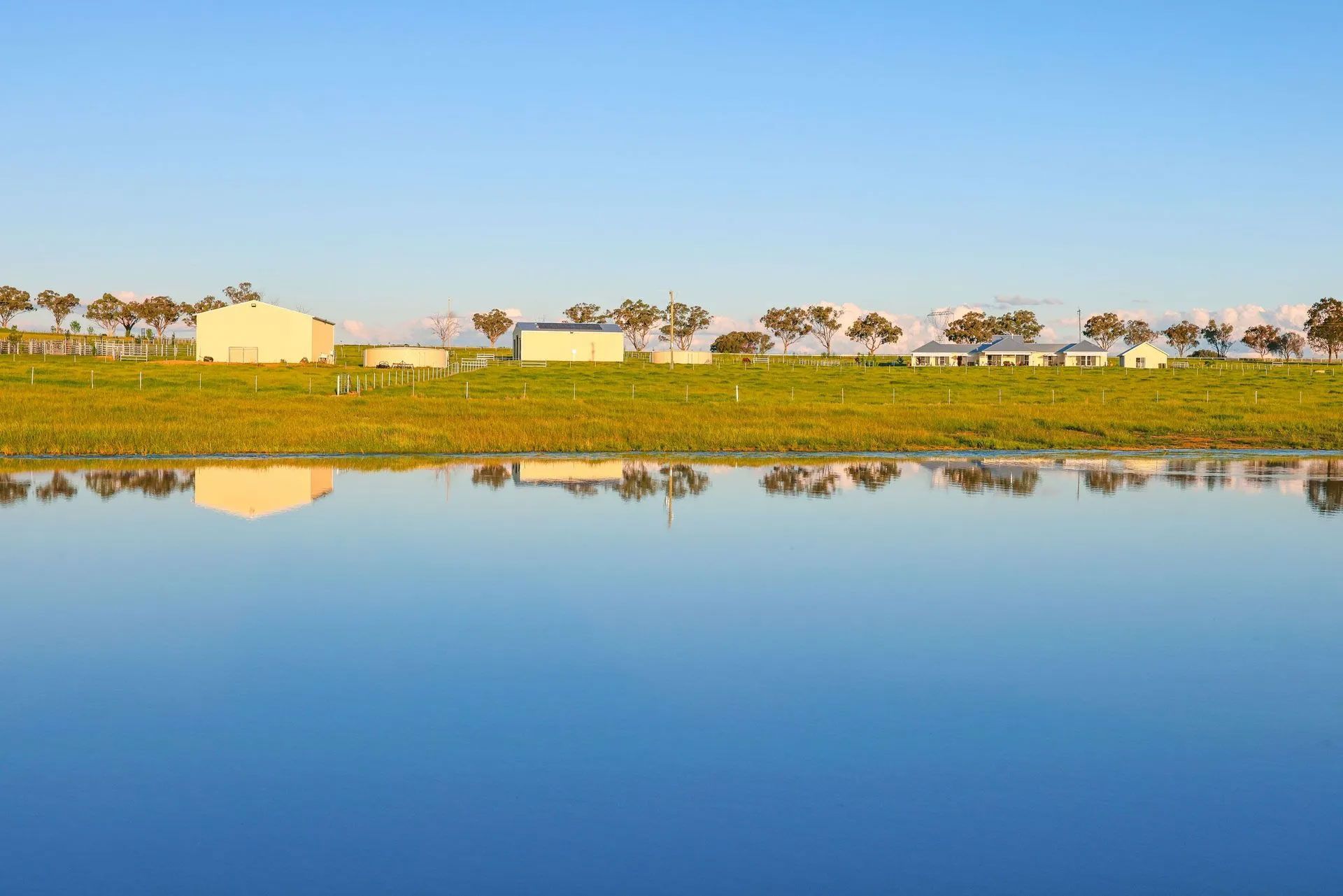 A large body of water with a reflection of a farm in it.