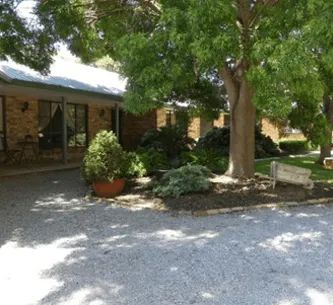 A house with a gravel driveway and trees in front of it