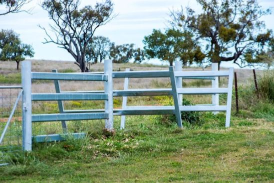 A white fence is sitting in the middle of a grassy field.