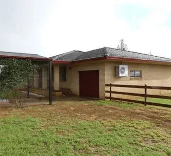A large brick house with a wooden fence in front of it.