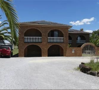 A red truck is parked in front of a large brick house