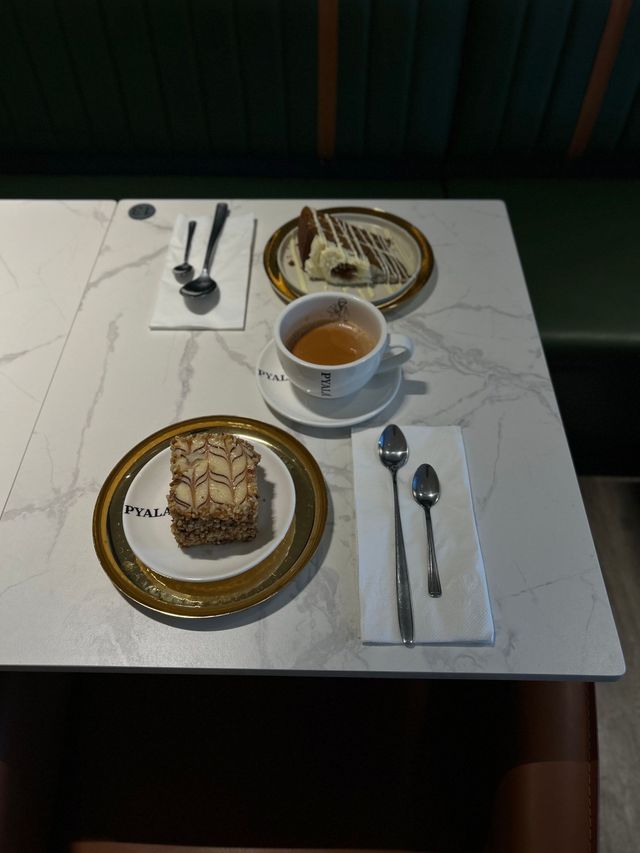 White marble table set with chai, two cakes on plates, and spoons.