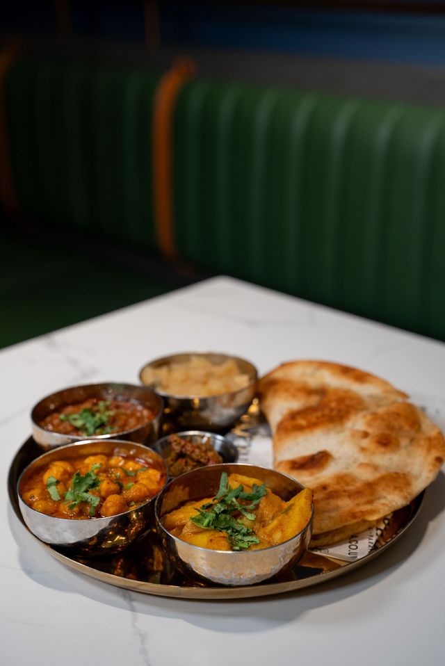 Cup of tea, slice of cake, spoons, and a napkin on a marble table.
