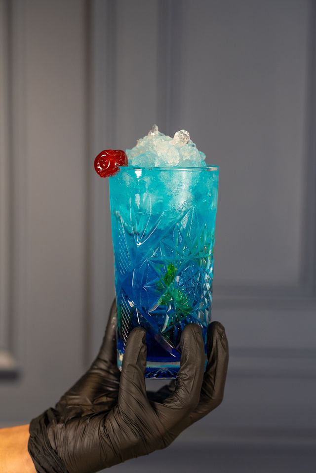 A clay cup of chai on a saucer on a table, with blue and green booth seating in the background.