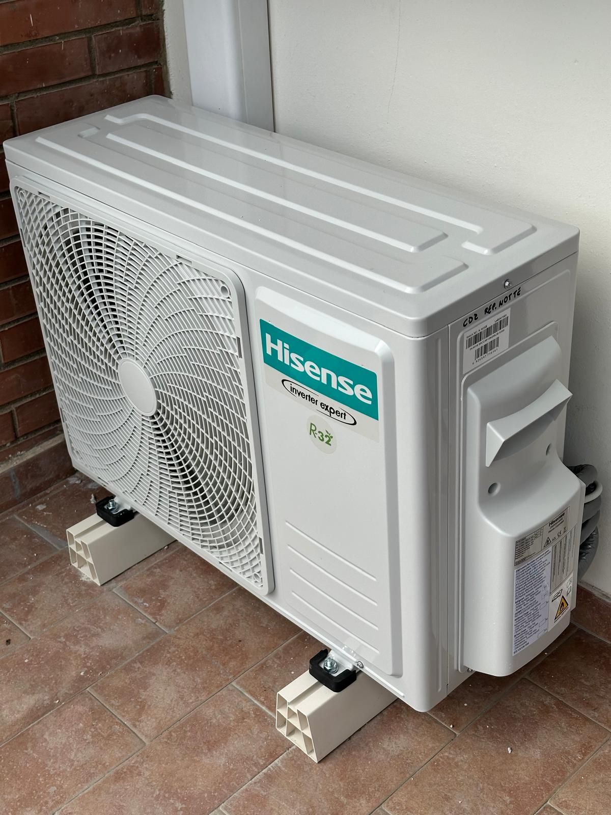 Un condizionatore d'aria bianco a parete installato in modo errato, con i cavi interni scoperti che pendono al di sotto.