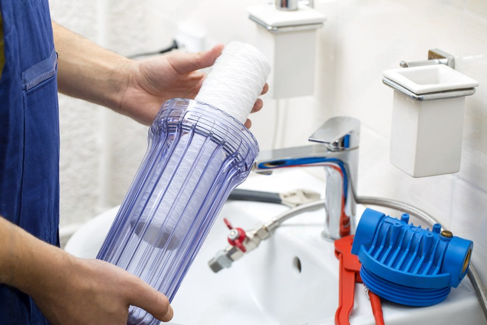 a person is holding a water filter in front of a sink .