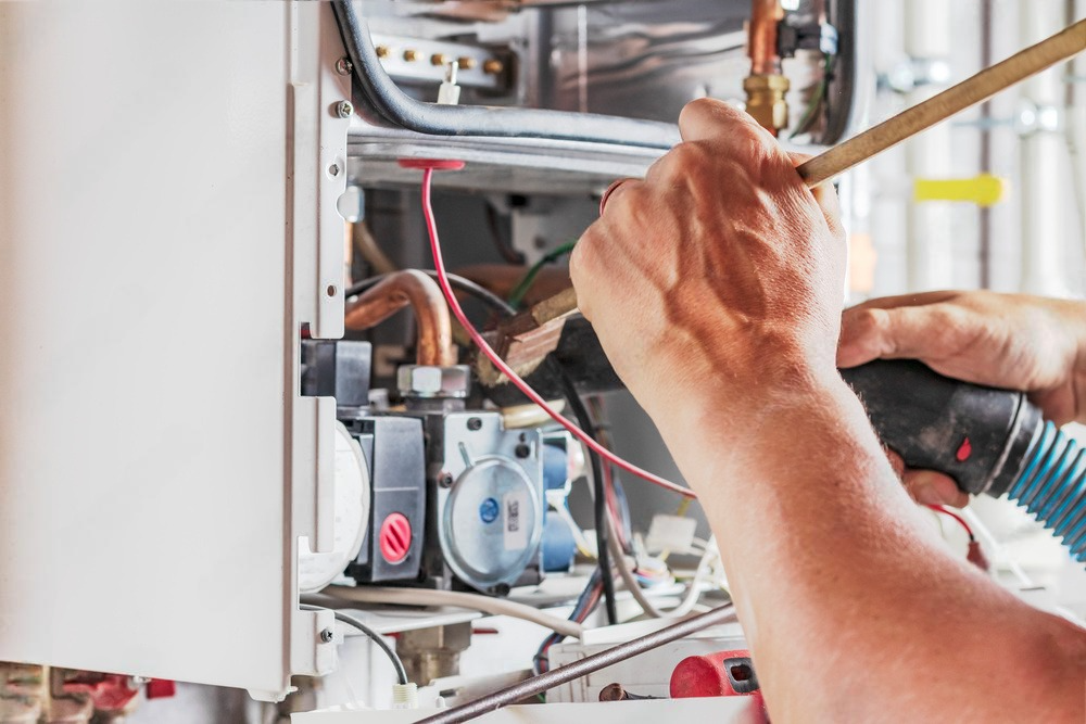 a man is working on a boiler with a vacuum cleaner .