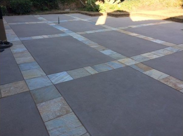 Concrete patio with stone tile borders in light blue and beige.