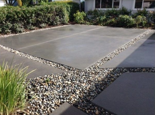 Concrete patio with gravel borders, set in a yard with greenery.