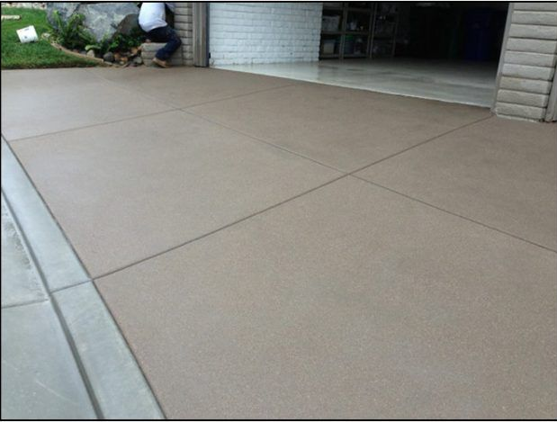 Newly poured and sealed concrete driveway. A person is visible in the background.