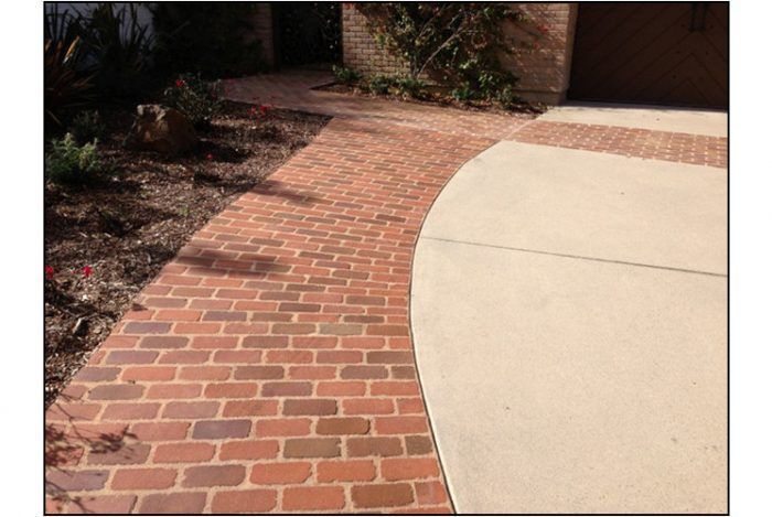 Brick pathway curving alongside a concrete driveway.