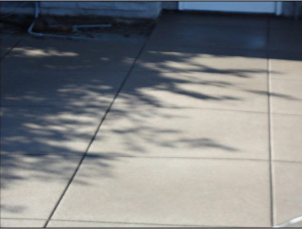 Concrete patio with shadows from overhead tree branches.