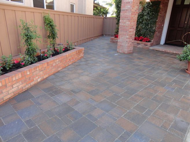 Brick patio with brick planters and a wooden fence; entry to a building.