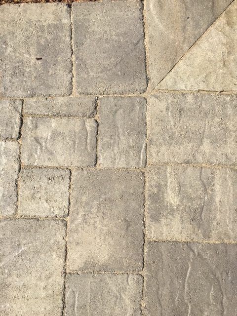 Close-up of gray stone pavers in a random rectangular pattern, one corner is a triangle.