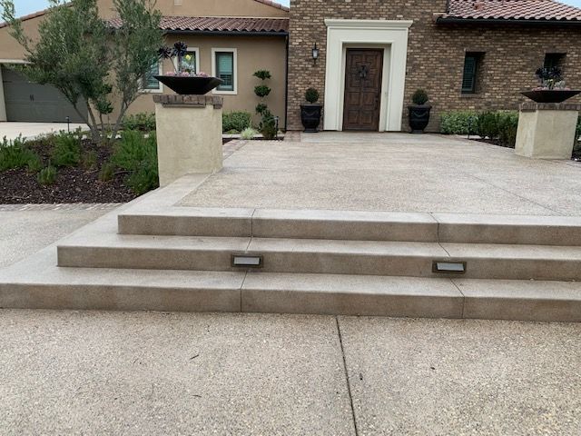 Stone steps leading to a house entrance with planters and decorative elements.
