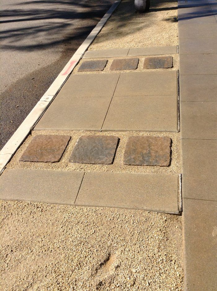 Sidewalk with paving stones and gravel. Some stones are inset, others are square. Road edge at left.