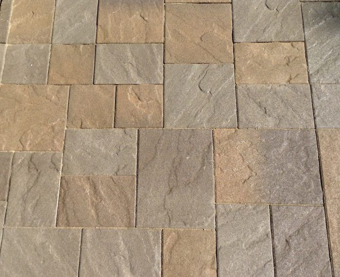 Stone patio with varying shades of tan and gray rectangular pavers.