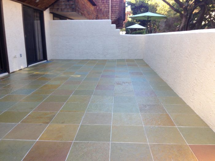 Patio with multicolored square tiles and white stucco walls.
