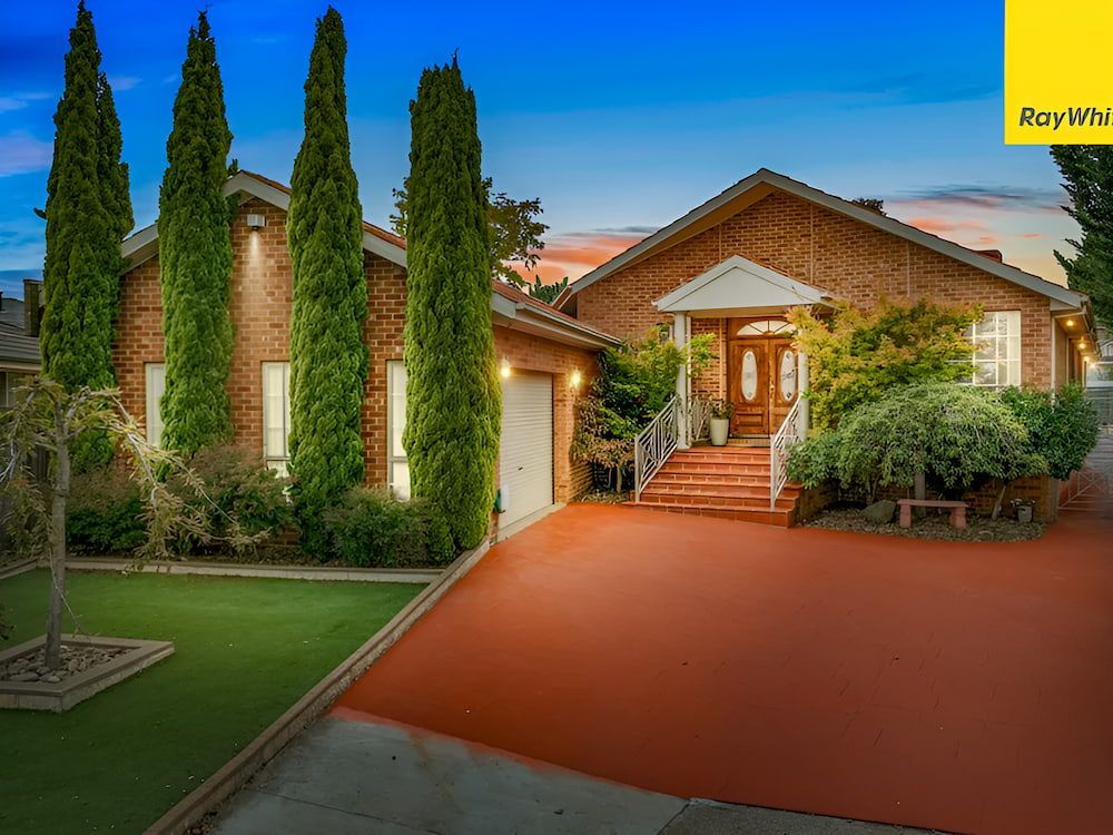 A Large Brick House With A Red Driveway And Trees In Front Of It — Romy Sidhu Ray White Weir Views In Melton, VIC