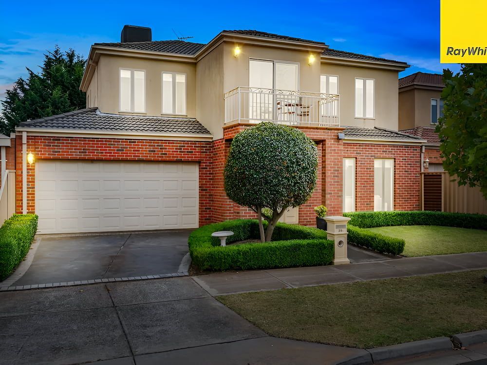 A Large Brick House With A White Garage Door — Romy Sidhu Ray White Weir Views In Melton, VIC