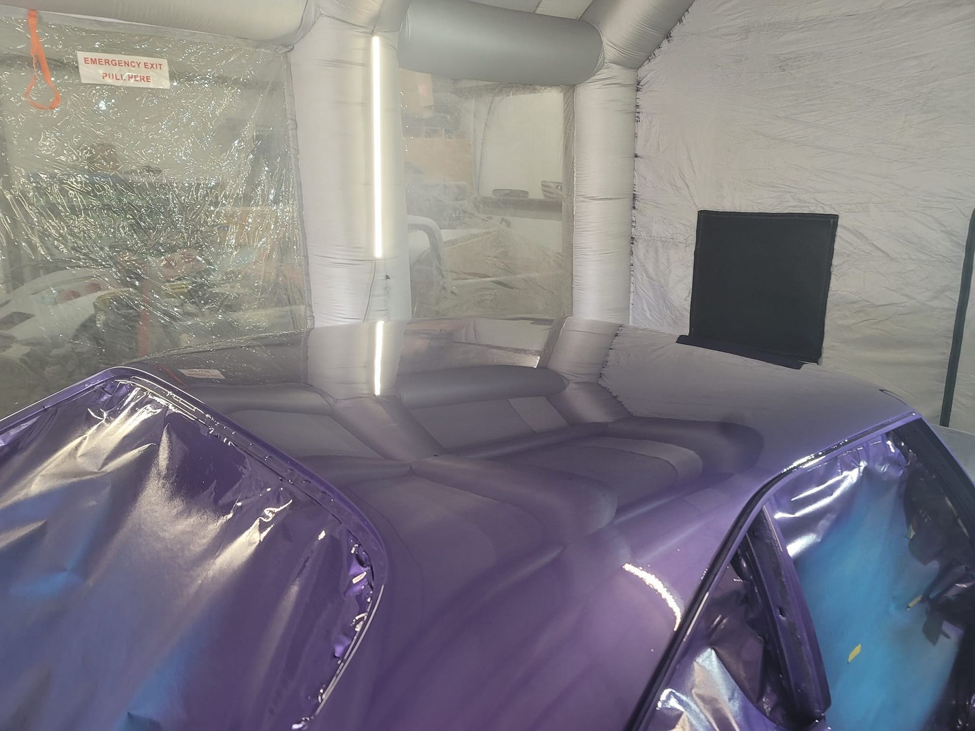 Purple car roof inside an inflatable paint booth.