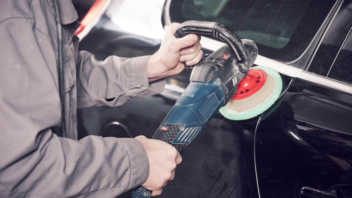 Person polishing a black car with a power buffer.