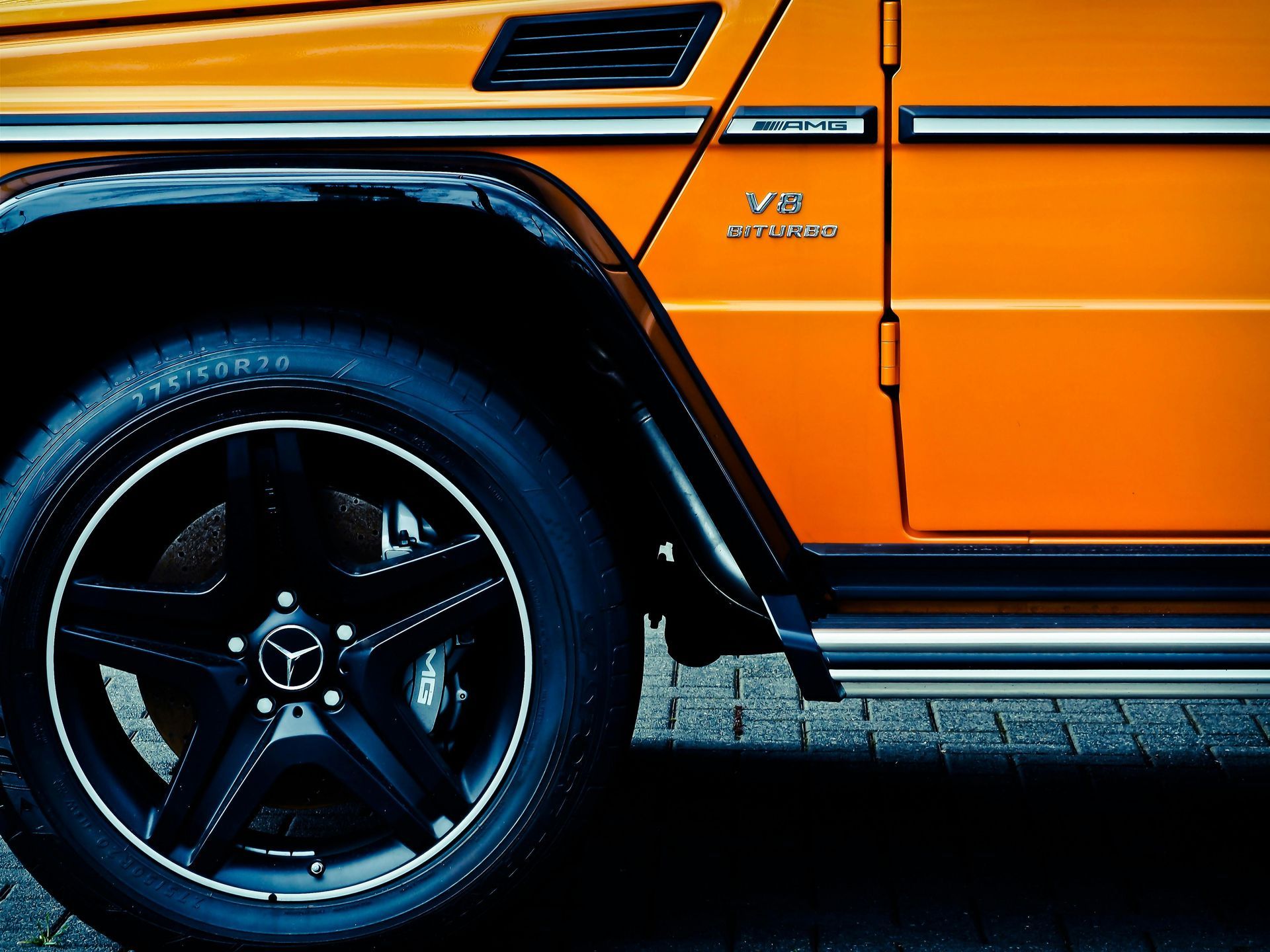 Orange Mercedes-Benz G-Class SUV, black rims, silver accents, and a