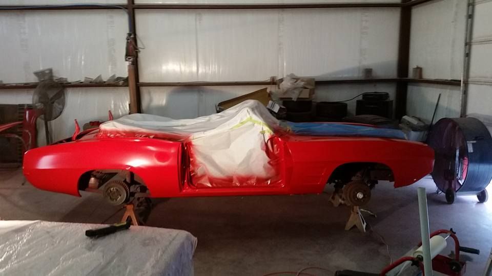 Red classic car, partially painted in a garage.