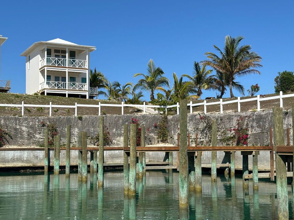 A dock with a house in the background and palm trees