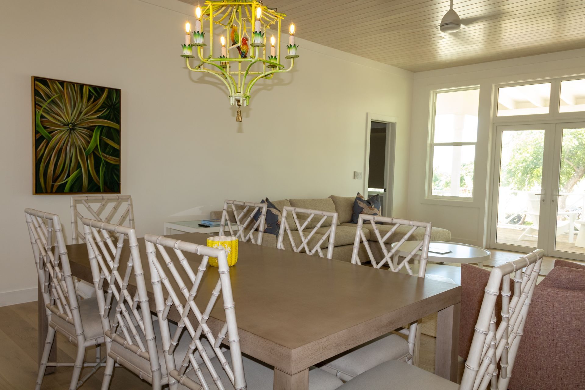 Dining room with light walls, long table, bamboo-style chairs, and chandelier.