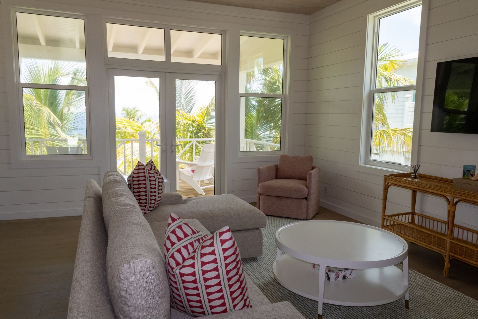 Living room with white walls, large windows, and a sofa with patterned pillows.