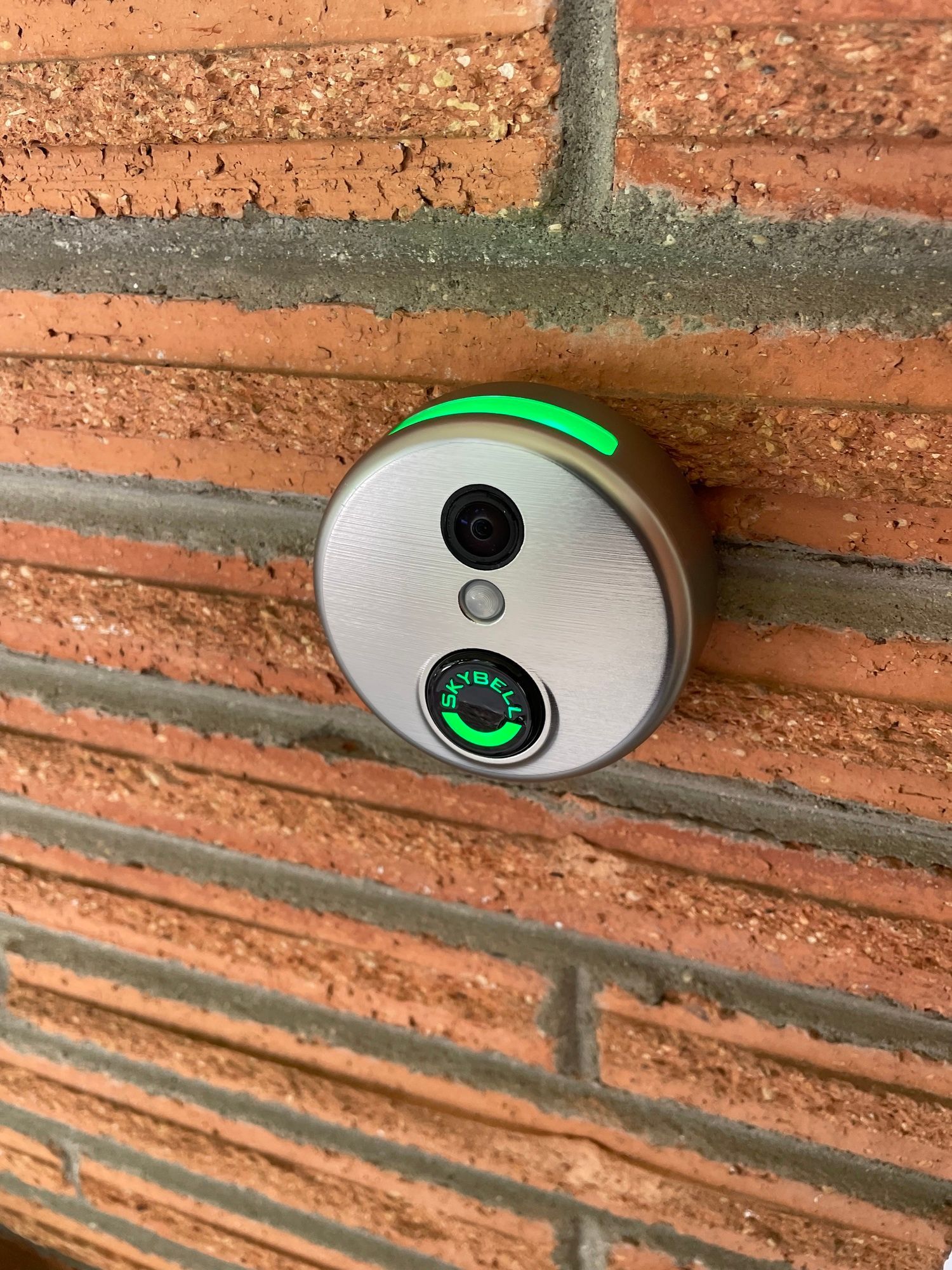 A doorbell with a camera attached to a brick wall.