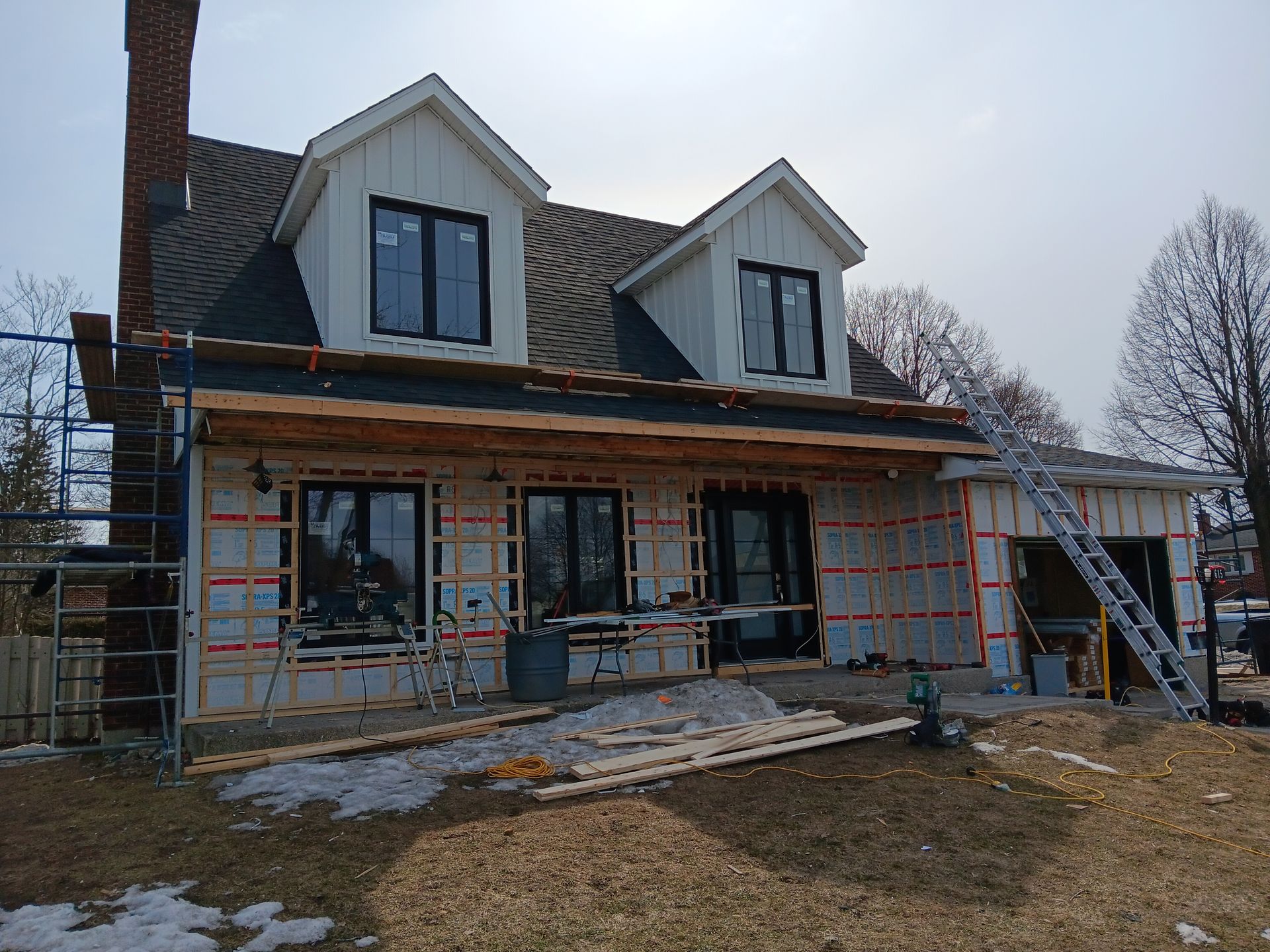 Une maison est en construction avec beaucoup de fenêtres et une cheminée.