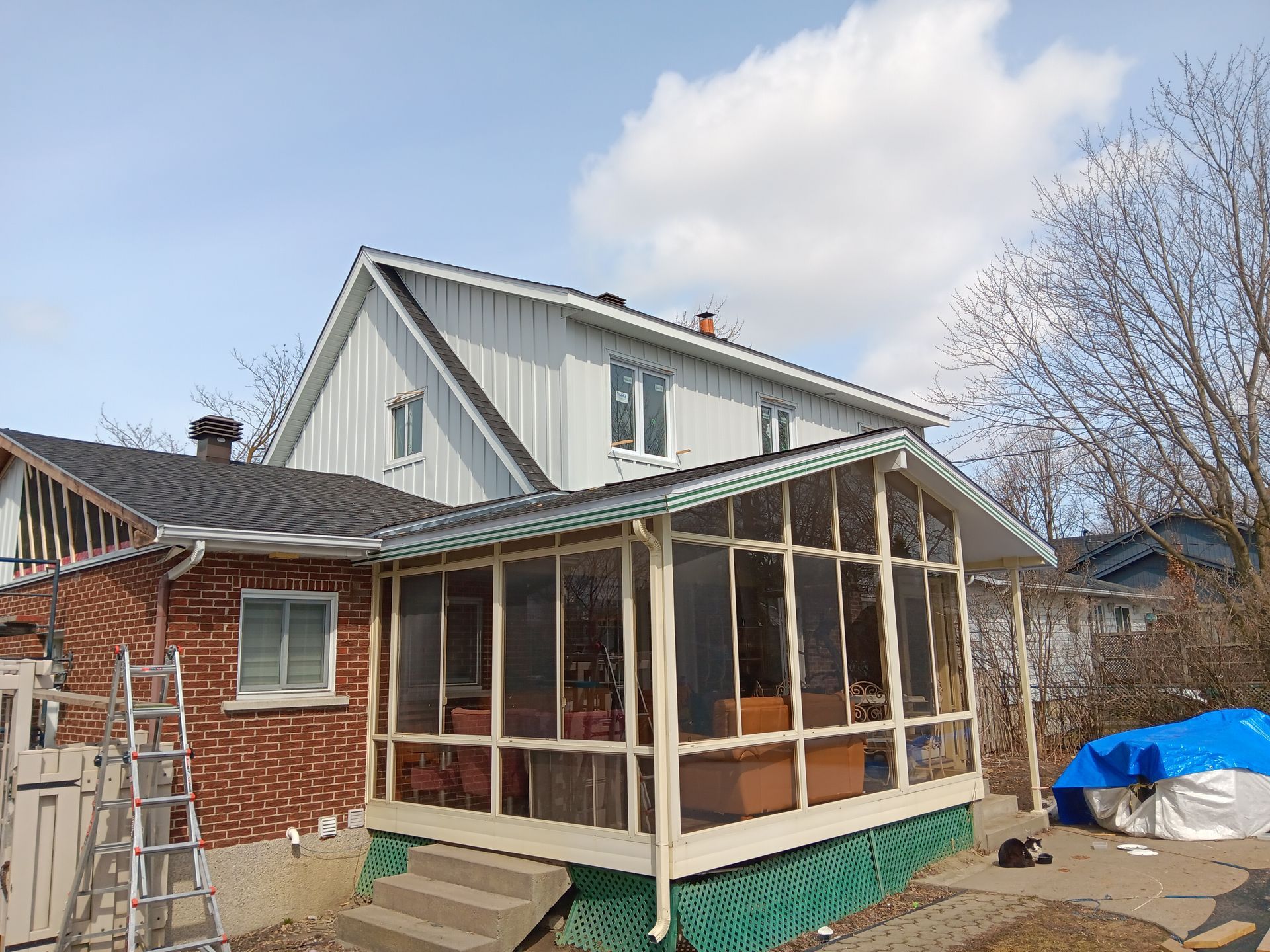 Une maison avec une véranda et une échelle devant