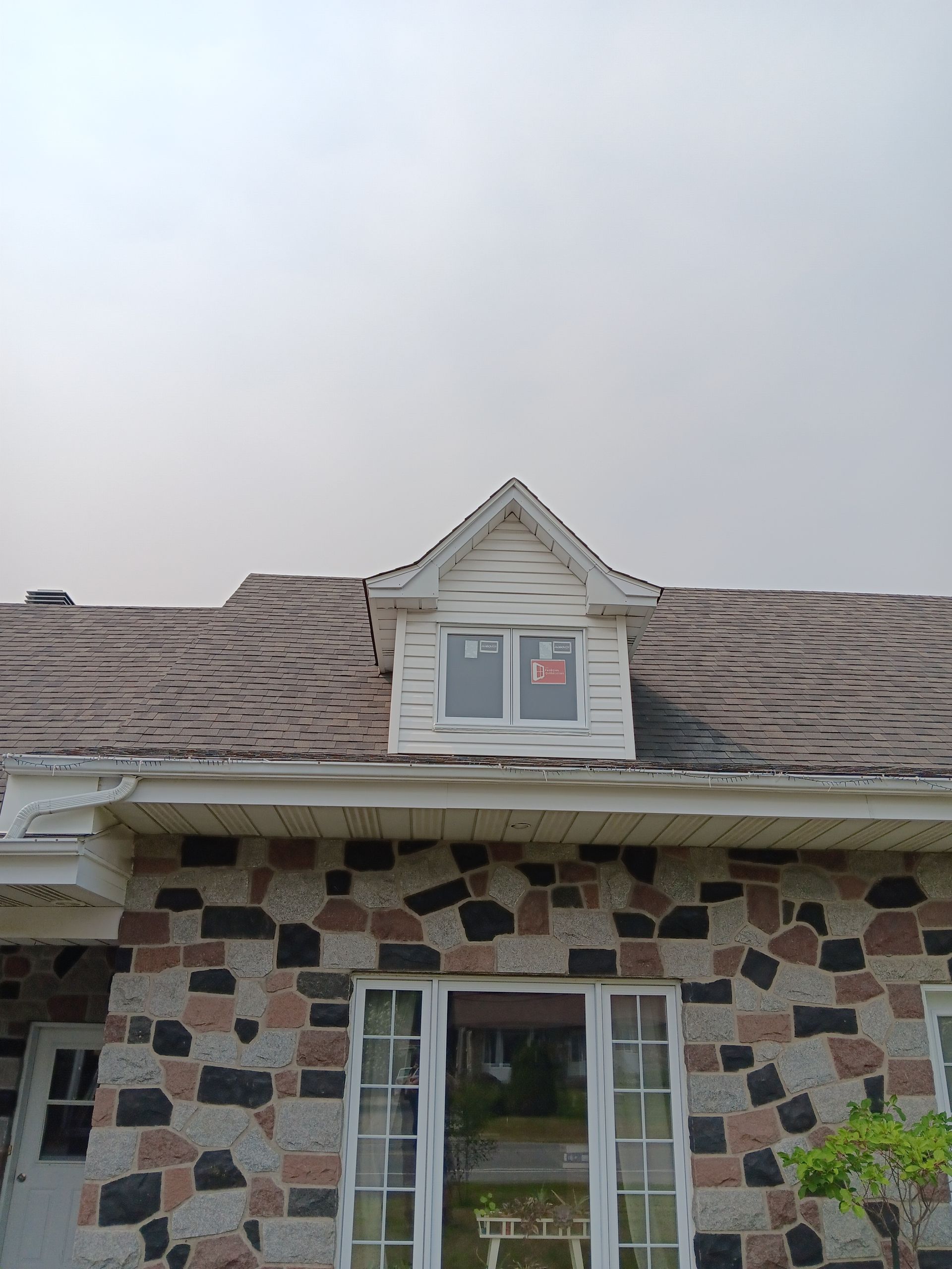 Une maison avec un toit sur lequel il y a une fenêtre.