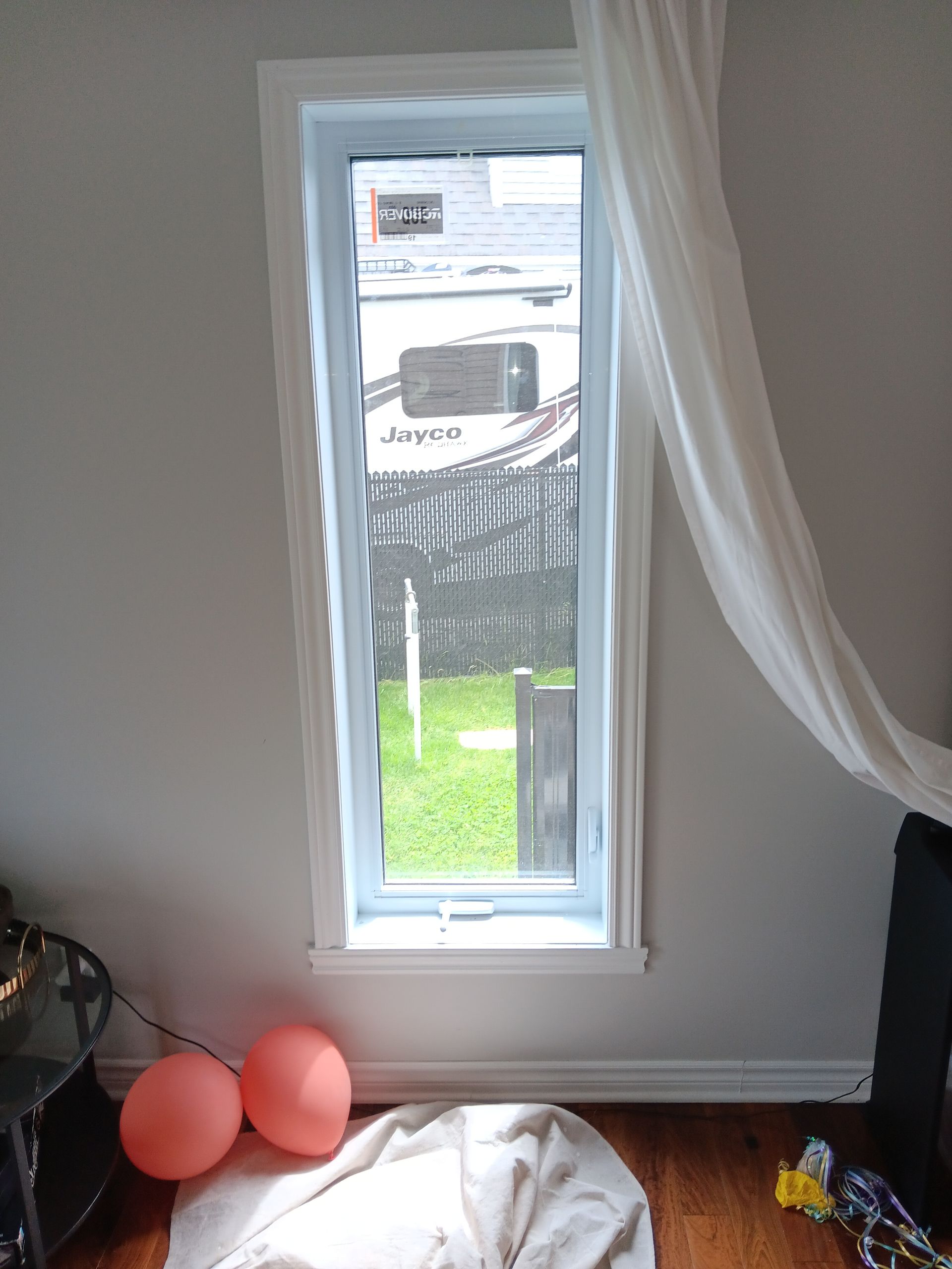 Une pièce avec une fenêtre et des ballons au sol.