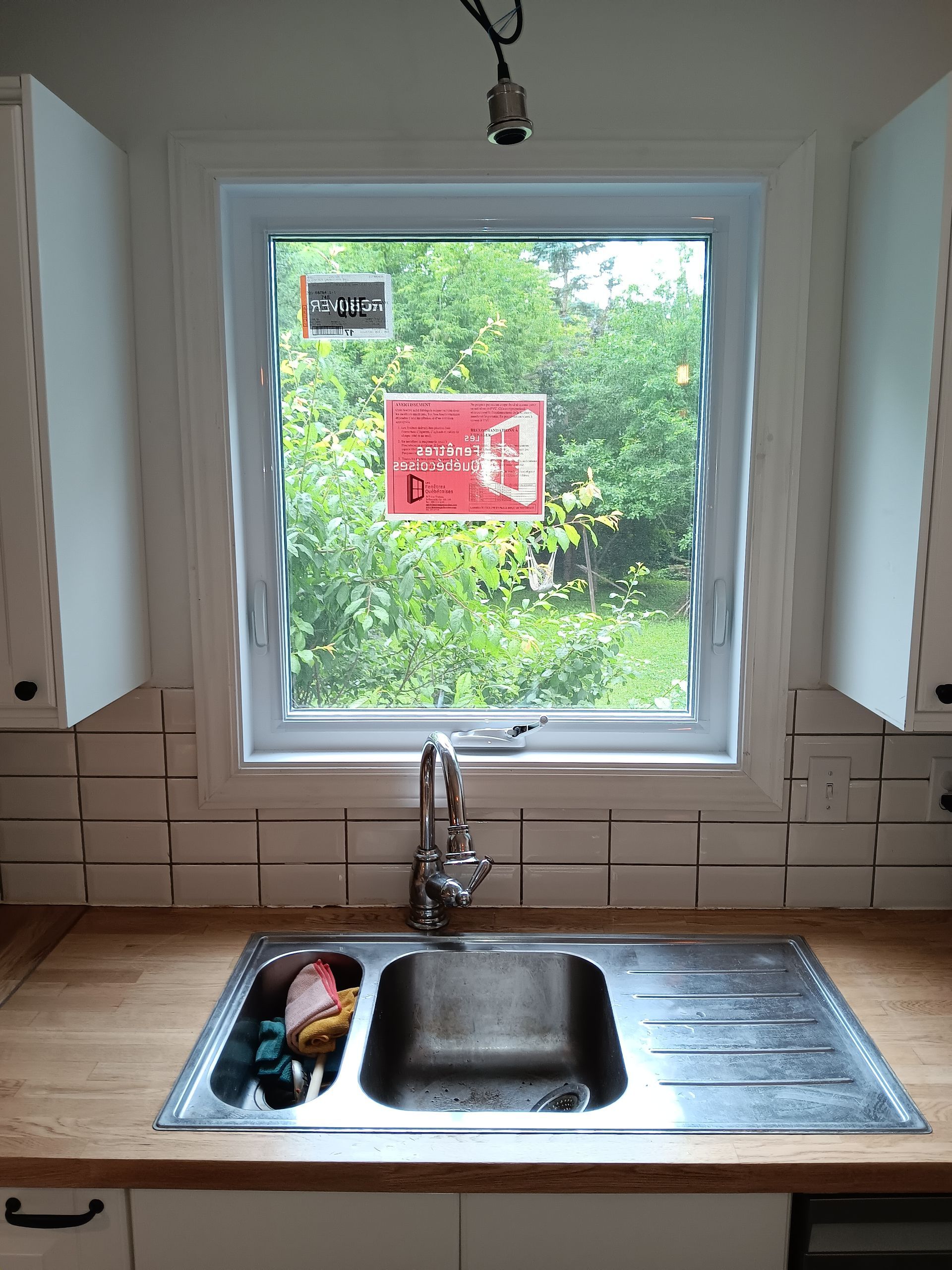 Une cuisine avec un évier et une fenêtre avec une pancarte dessus.