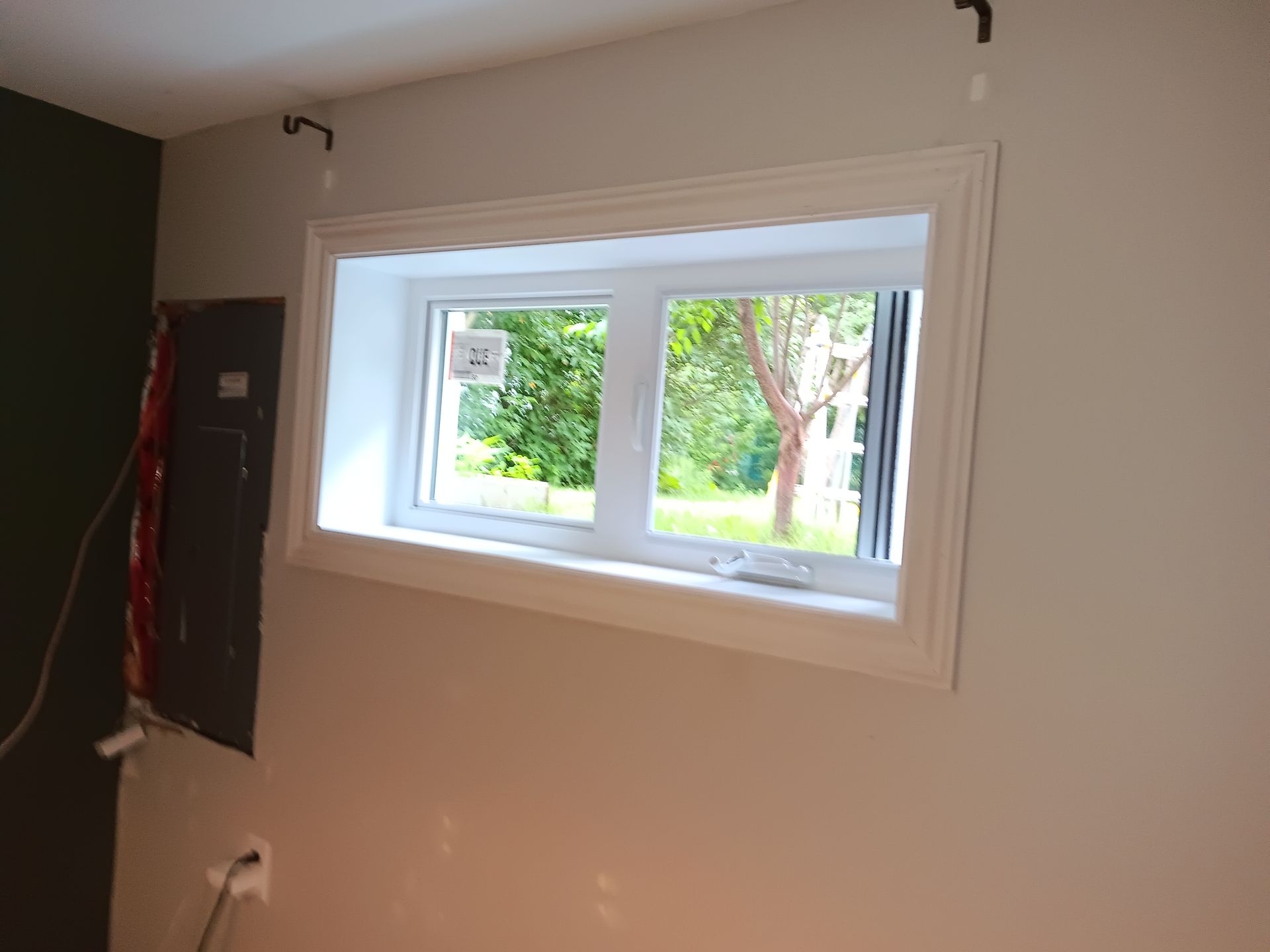 Une fenêtre blanche est posée sur un mur blanc dans une pièce.