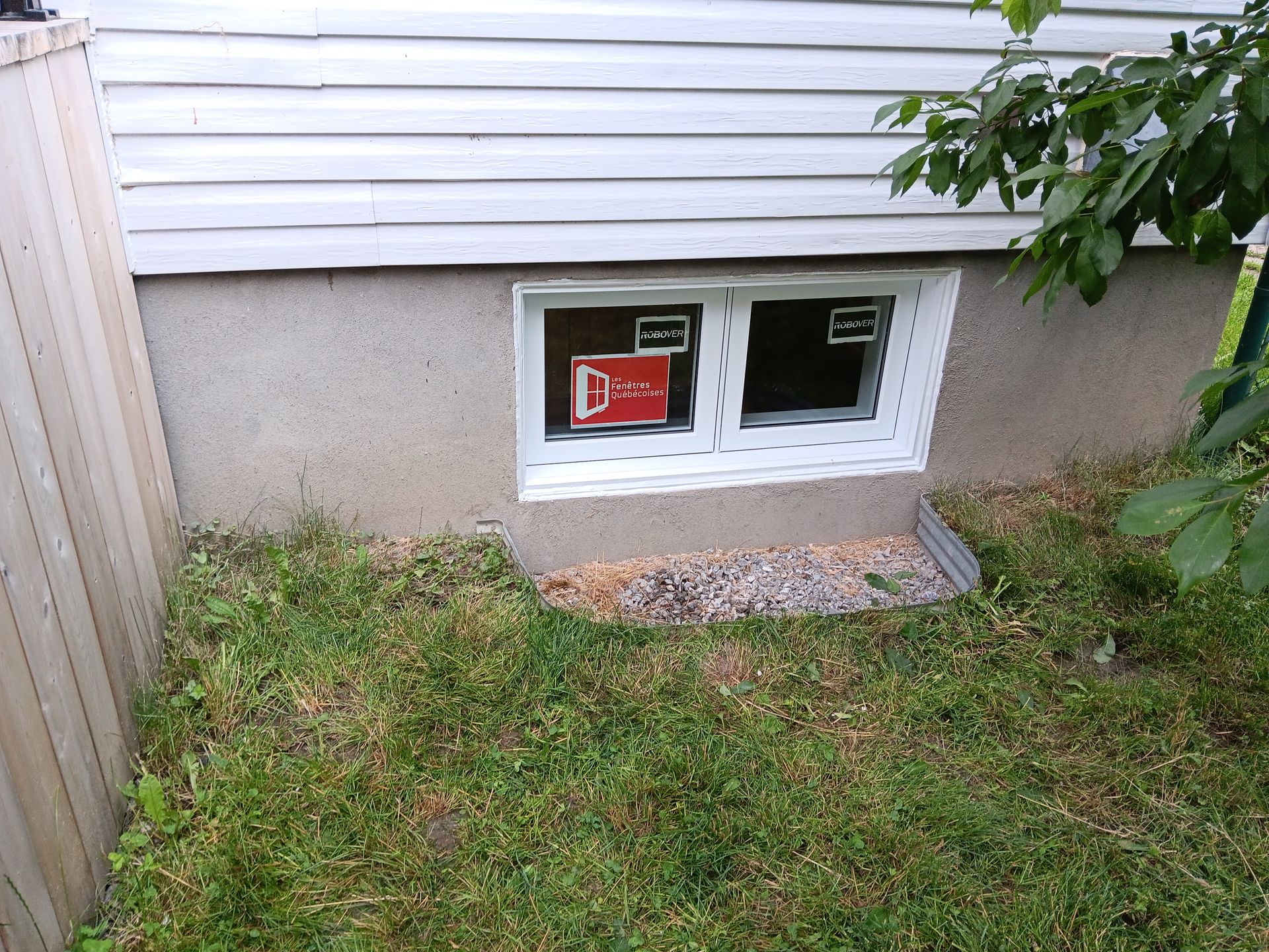 Une fenêtre au sous-sol d’une maison porte une pancarte indiquant d.