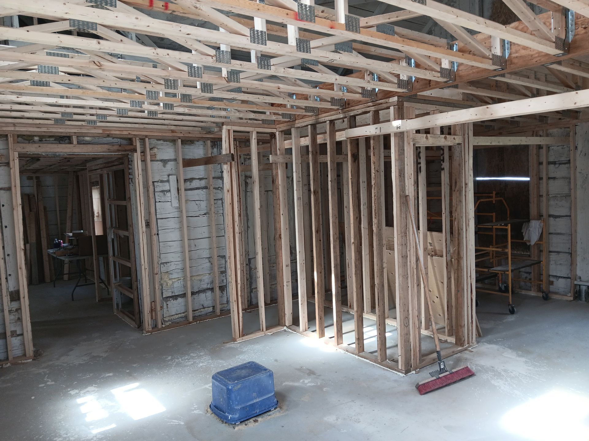 Une pièce en construction avec des poutres en bois et un balai.