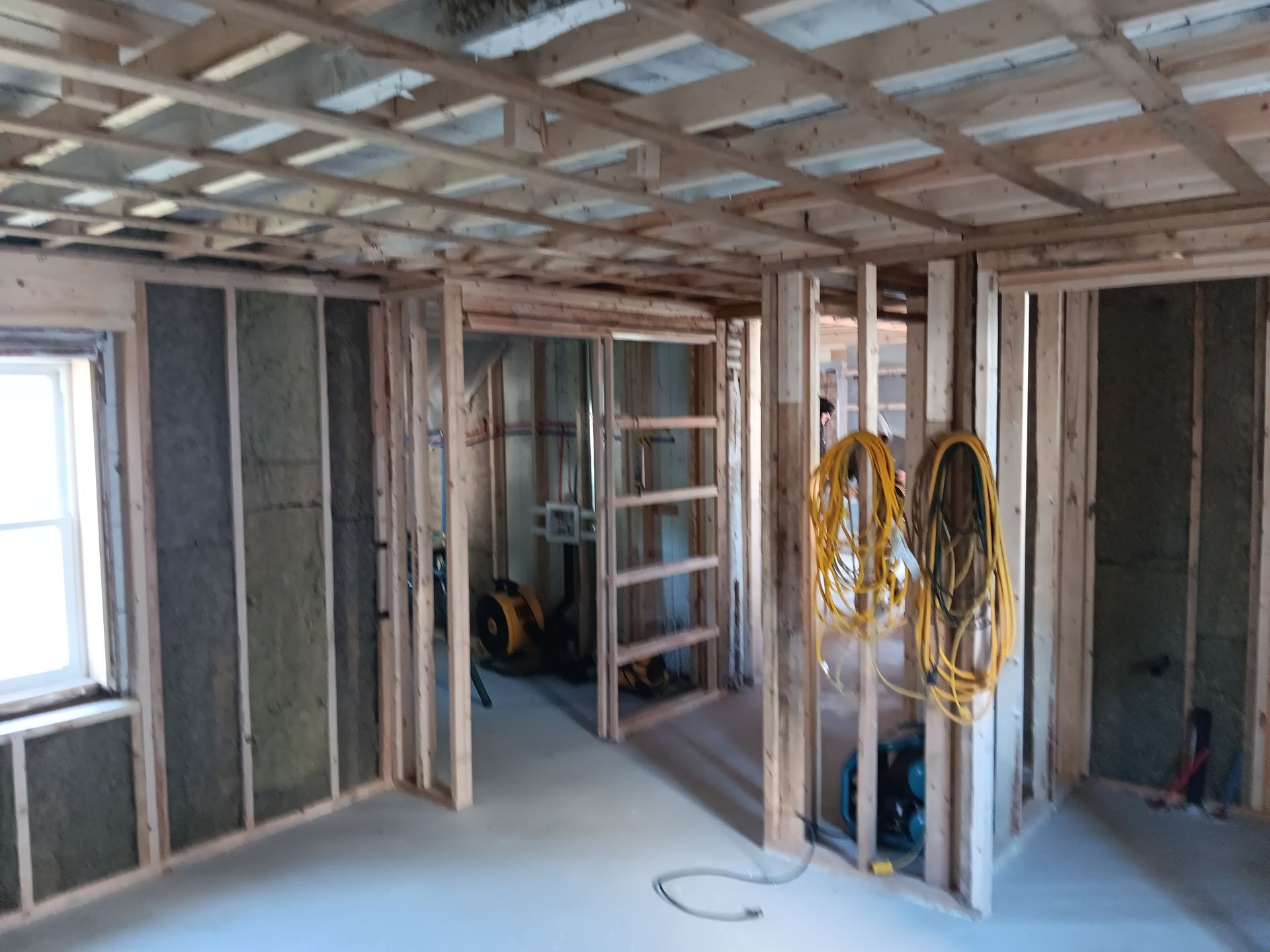 Une pièce dans une maison en construction avec une échelle et un ventilateur.