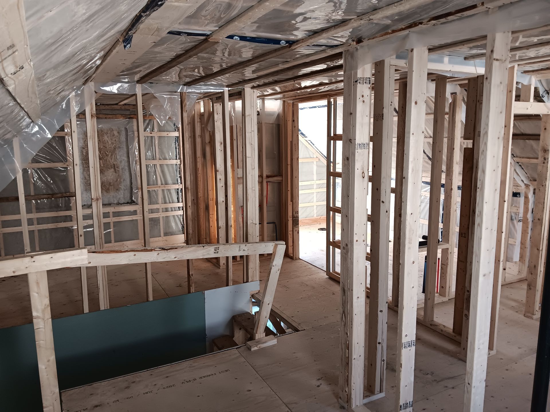 L'intérieur d'une maison en construction avec des poutres en bois et un escalier.