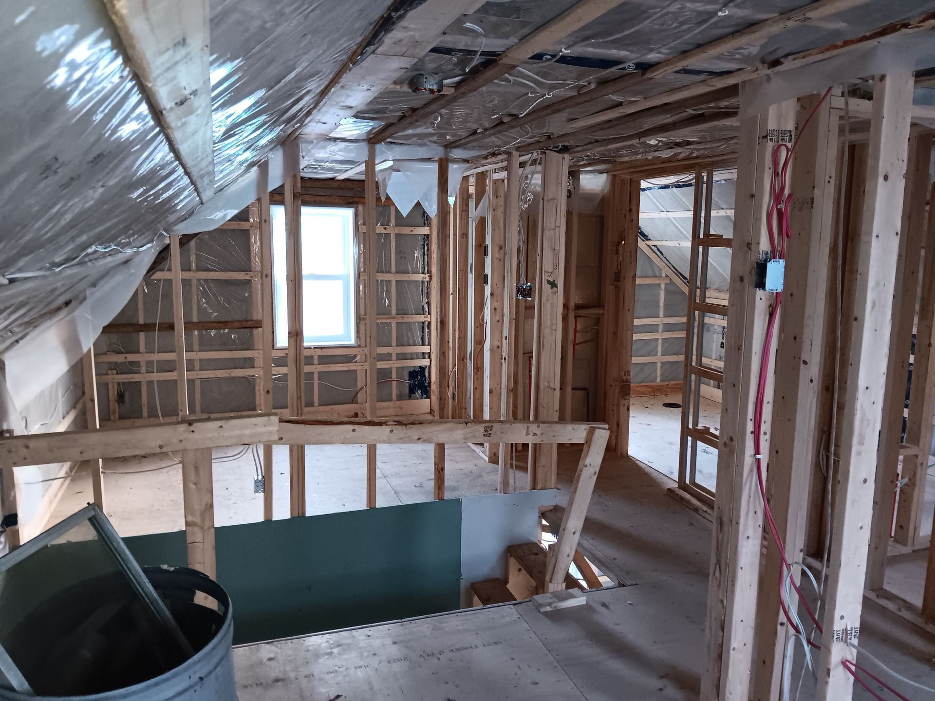 L'intérieur d'une maison en construction avec un seau au milieu de la pièce.