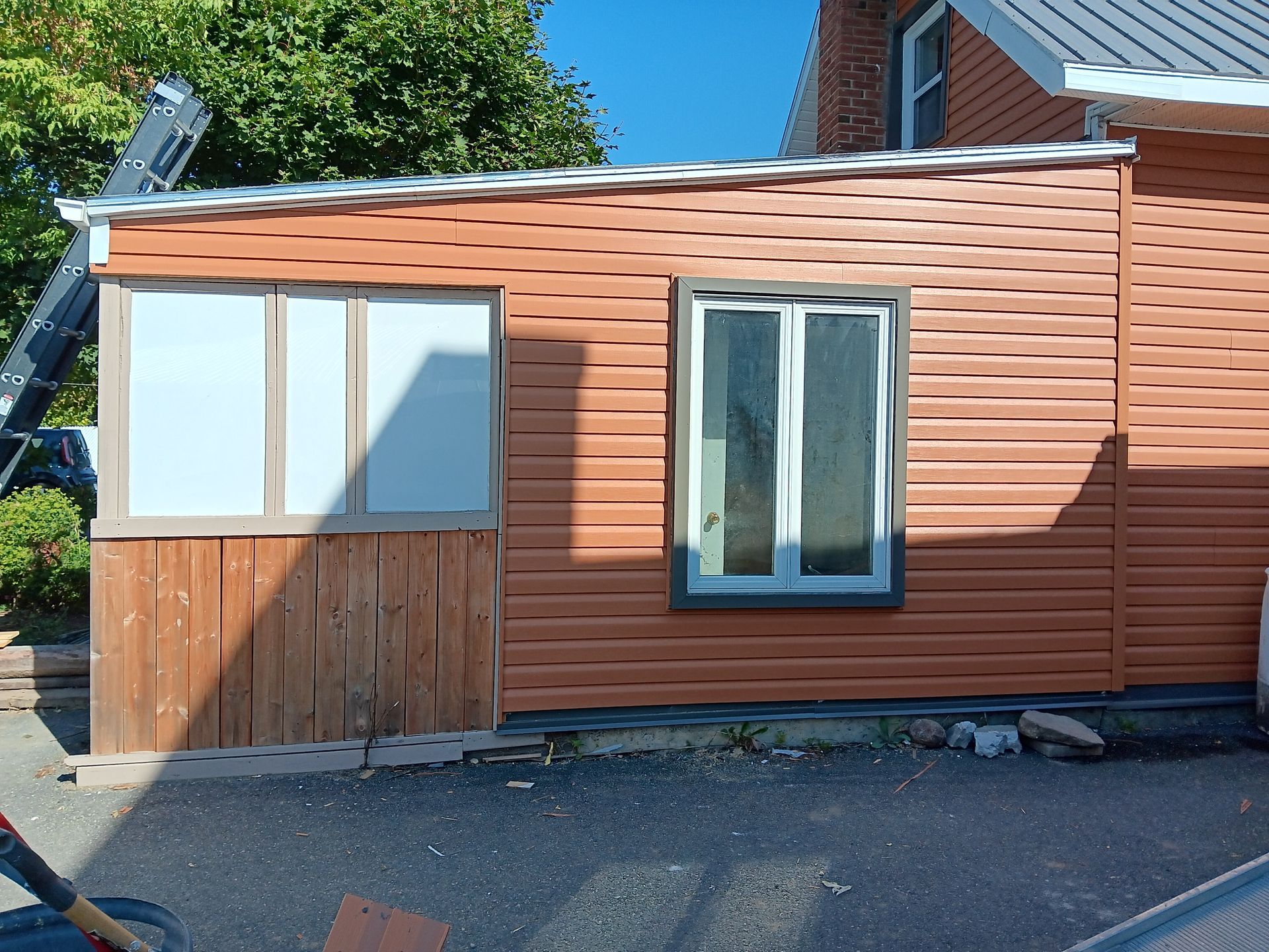 Une maison en bois avec une fenêtre et une échelle devant