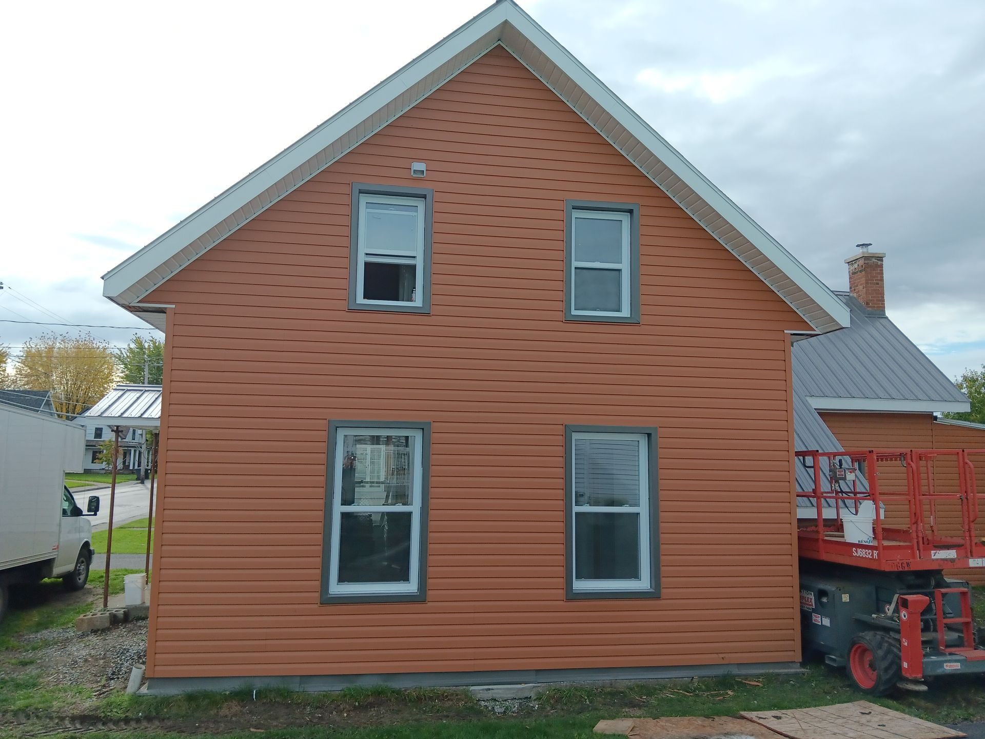 Une grande maison orange avec un chariot élévateur garé devant.