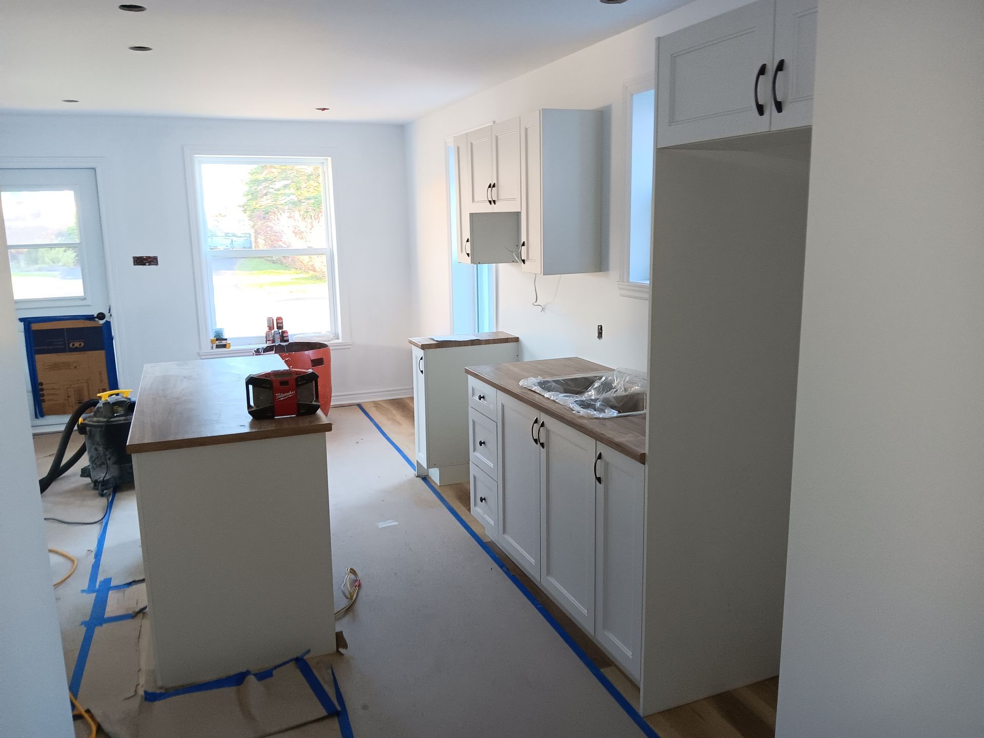 Une cuisine en construction avec des armoires blanches et un évier